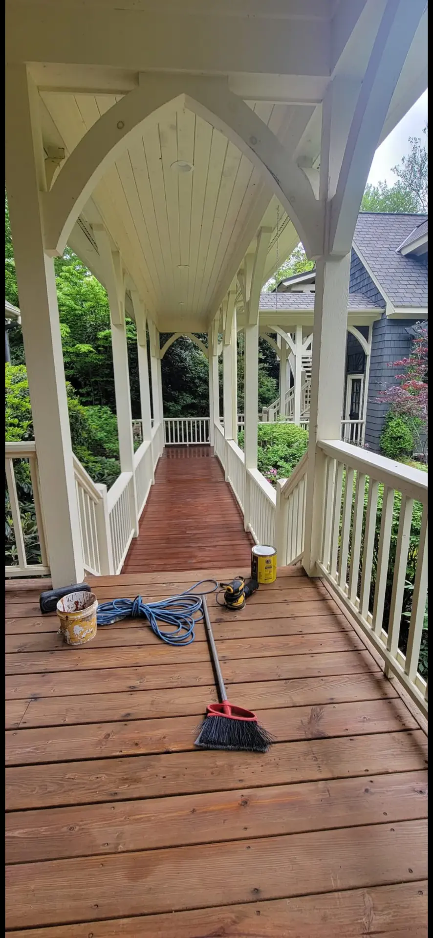 Porch arches and railings painted soft cream over a stained wood deck