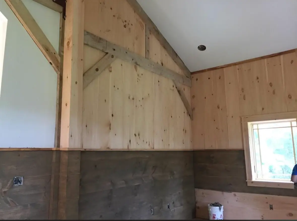 Pine paneled interior wall with stained wainscot and white painted ceiling