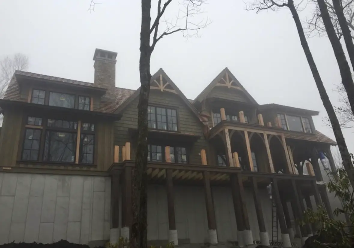 Timber frame mountain lodge exterior stained olive and dark brown in the fog