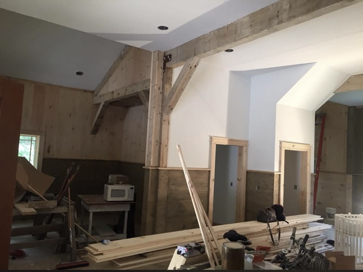 Great room interior with timber beams, pine paneling and freshly painted white ceilings