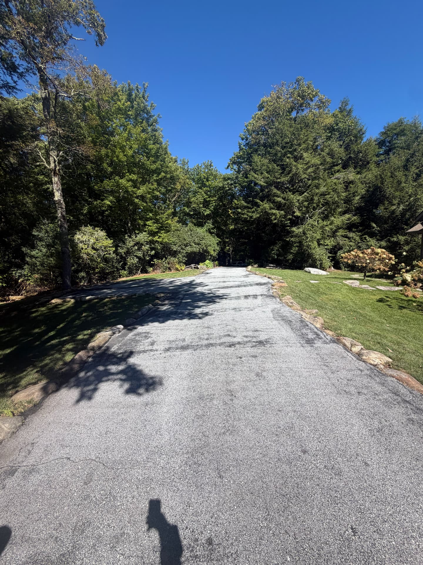 Long faded asphalt driveway prepped and ready for sealcoating under a blue sky