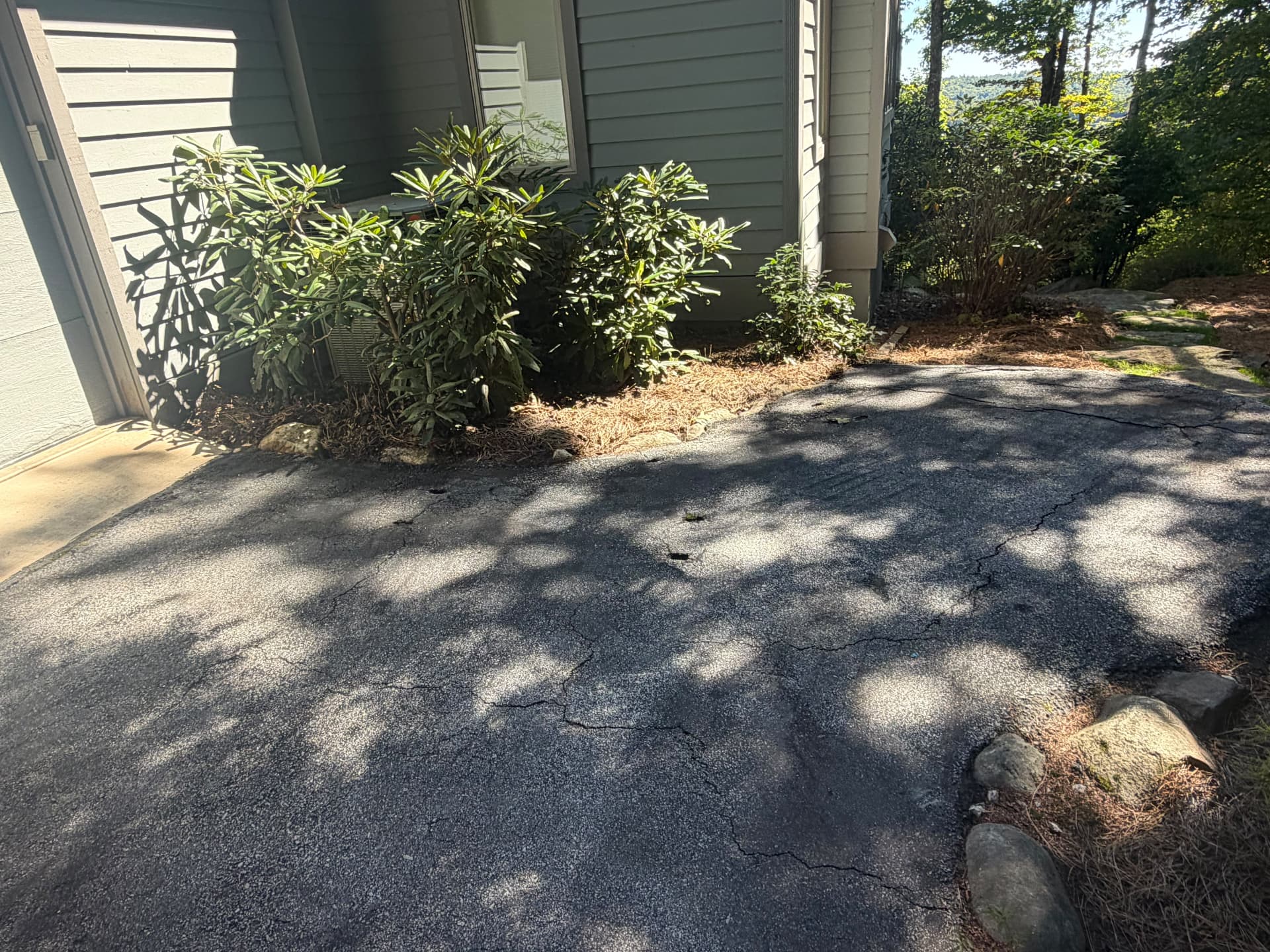 Side driveway near a garage with cracks filled and fresh black sealer applied